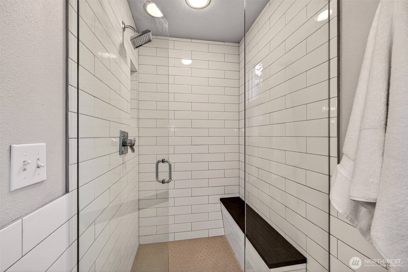 The oversized walk-in shower is a genuine luxury — floor-to-ceiling subway tile, a built-in bench seat, rainfall-style showerhead, and a frameless glass enclosure that keeps the space feeling open and airy. It's the kind of shower that makes you appreciate coming home.