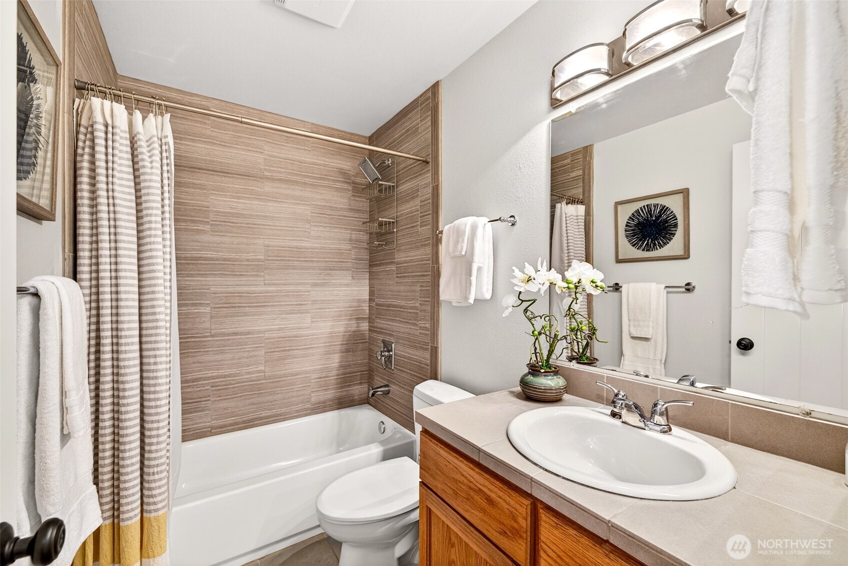 Conveniently located to serve the secondary bedrooms, the full hall bath offers a full tub and shower combination with a wood-look tile surround, single vanity, and a warm, well-lit layout that handles daily routines efficiently. It's a solid, functional bathroom that rounds out the home's complete bath package.
