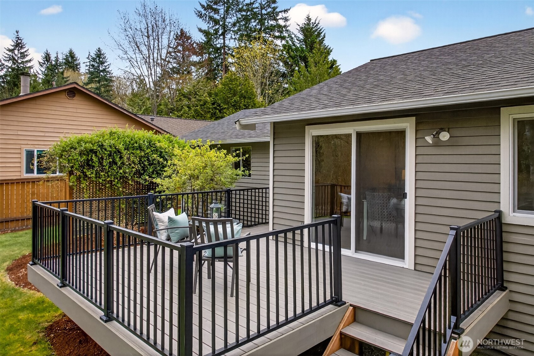 The deck connects directly to the main living area through sliding glass doors, making the transition from indoor dining to outdoor relaxation completely effortless. The deck's generous footprint, black rail system, and stepped access to the yard make it as functional as it is attractive.