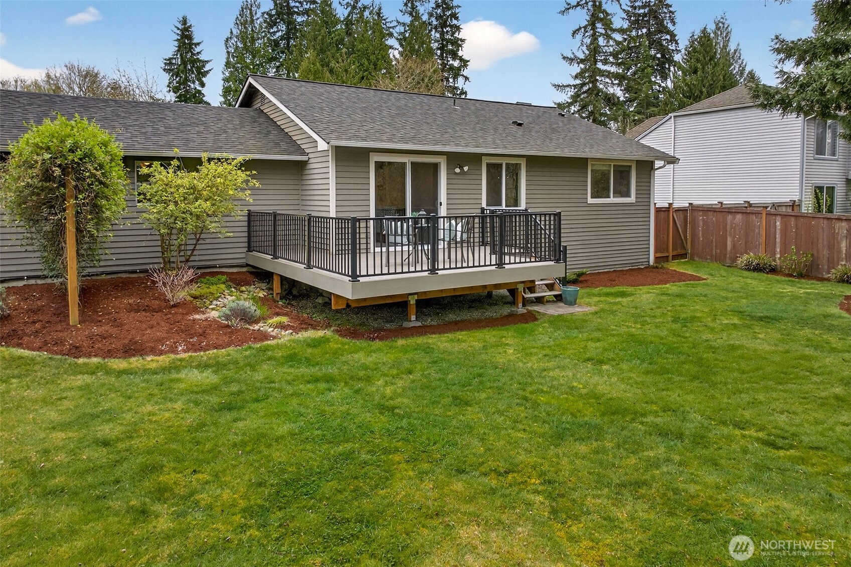 The rear of the home presents a clean, well-maintained profile anchored by the 2021 roof, updated deck, and a level, fully fenced backyard that's ready for immediate enjoyment. The combination of a usable lawn, established plantings, and a private deck creates a complete outdoor living package.