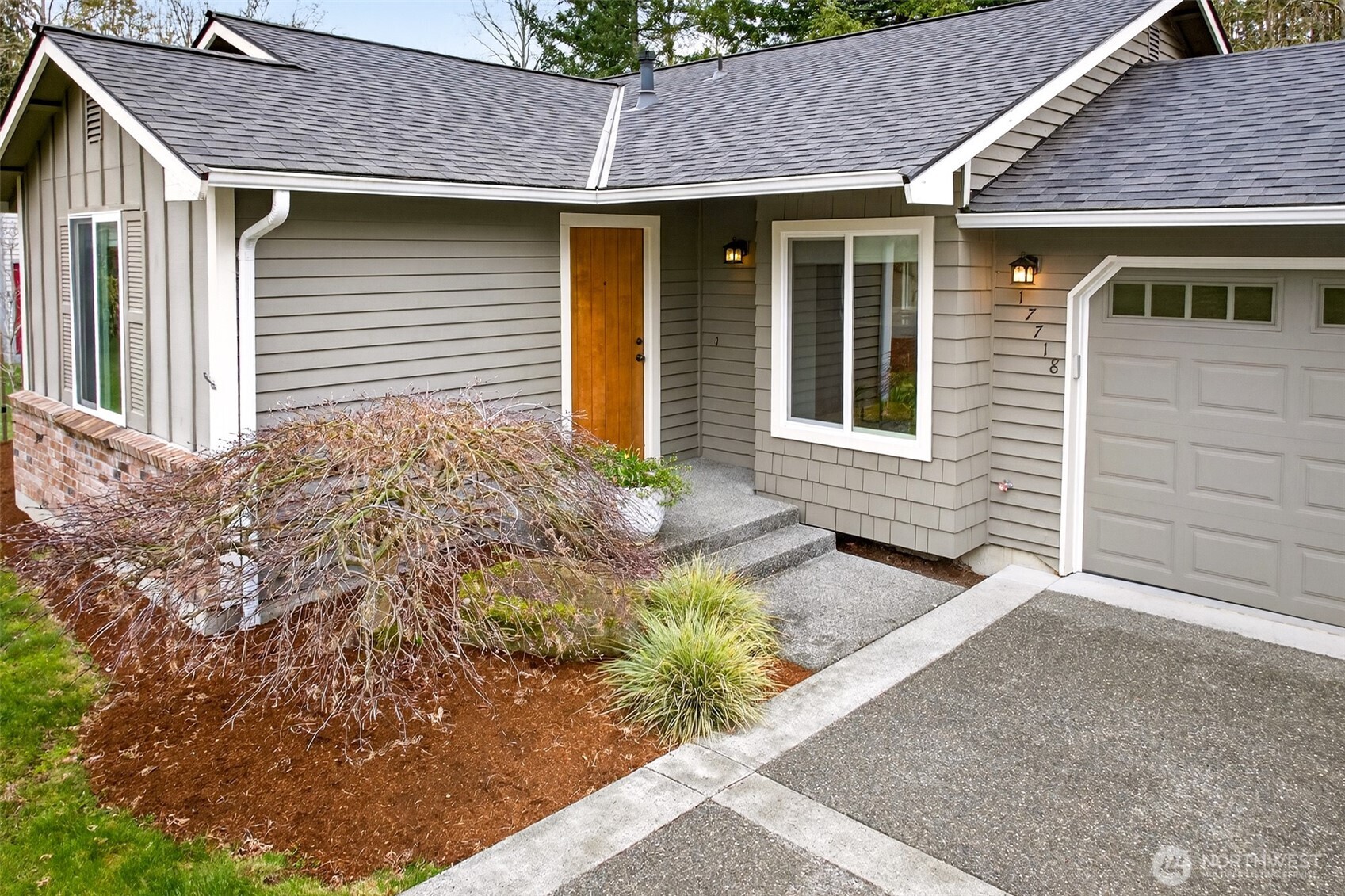 A rich wood-tone front door and craftsman-style wall sconces create a warm, inviting entry that signals quality the moment you arrive. The thoughtfully landscaped approach — featuring a sculptural Japanese maple and ornamental grasses — adds refined curb appeal that photographs beautifully in every season.