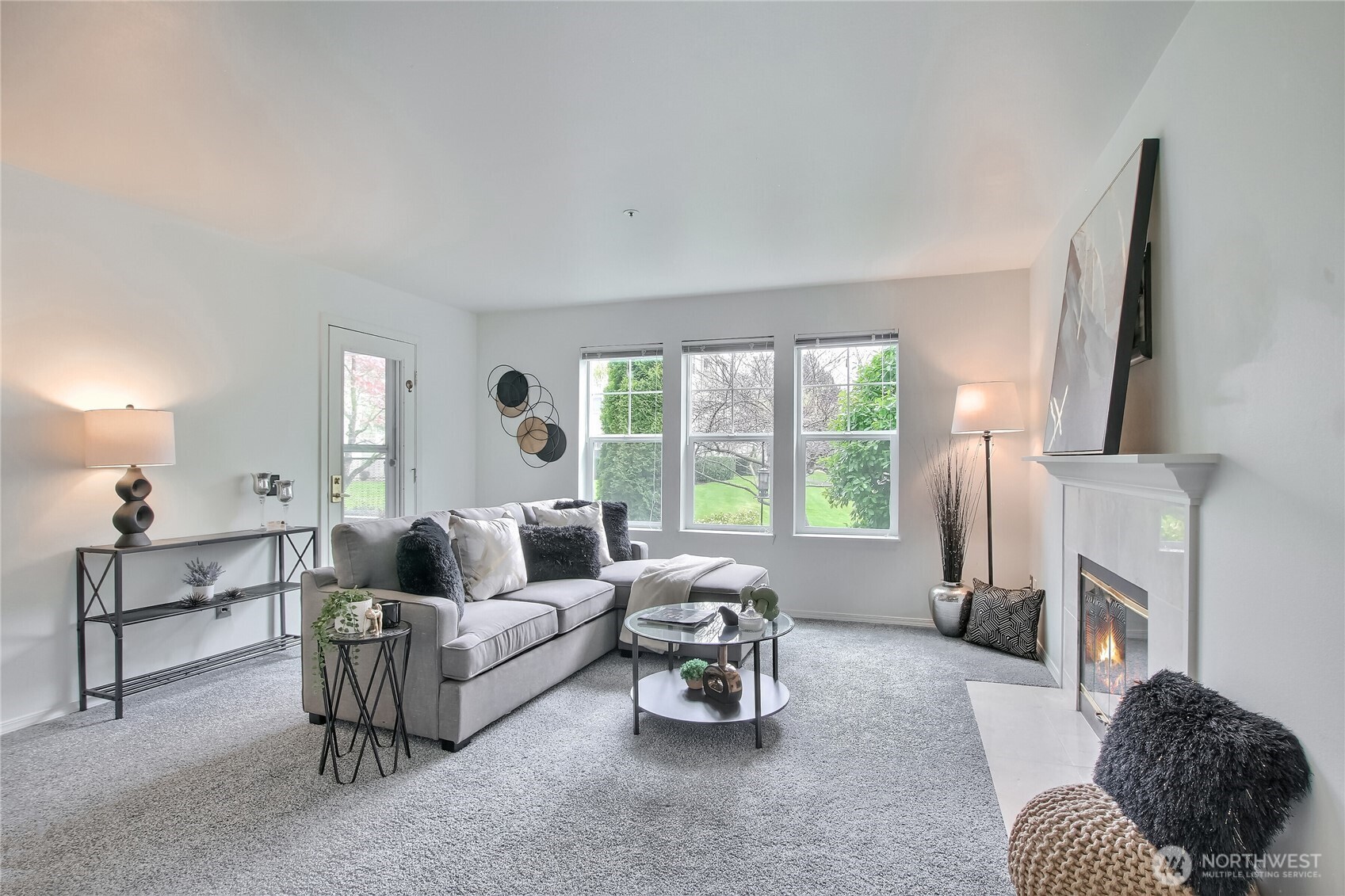 Large living area with wood burning fireplace, (App added flame), and door to patio.