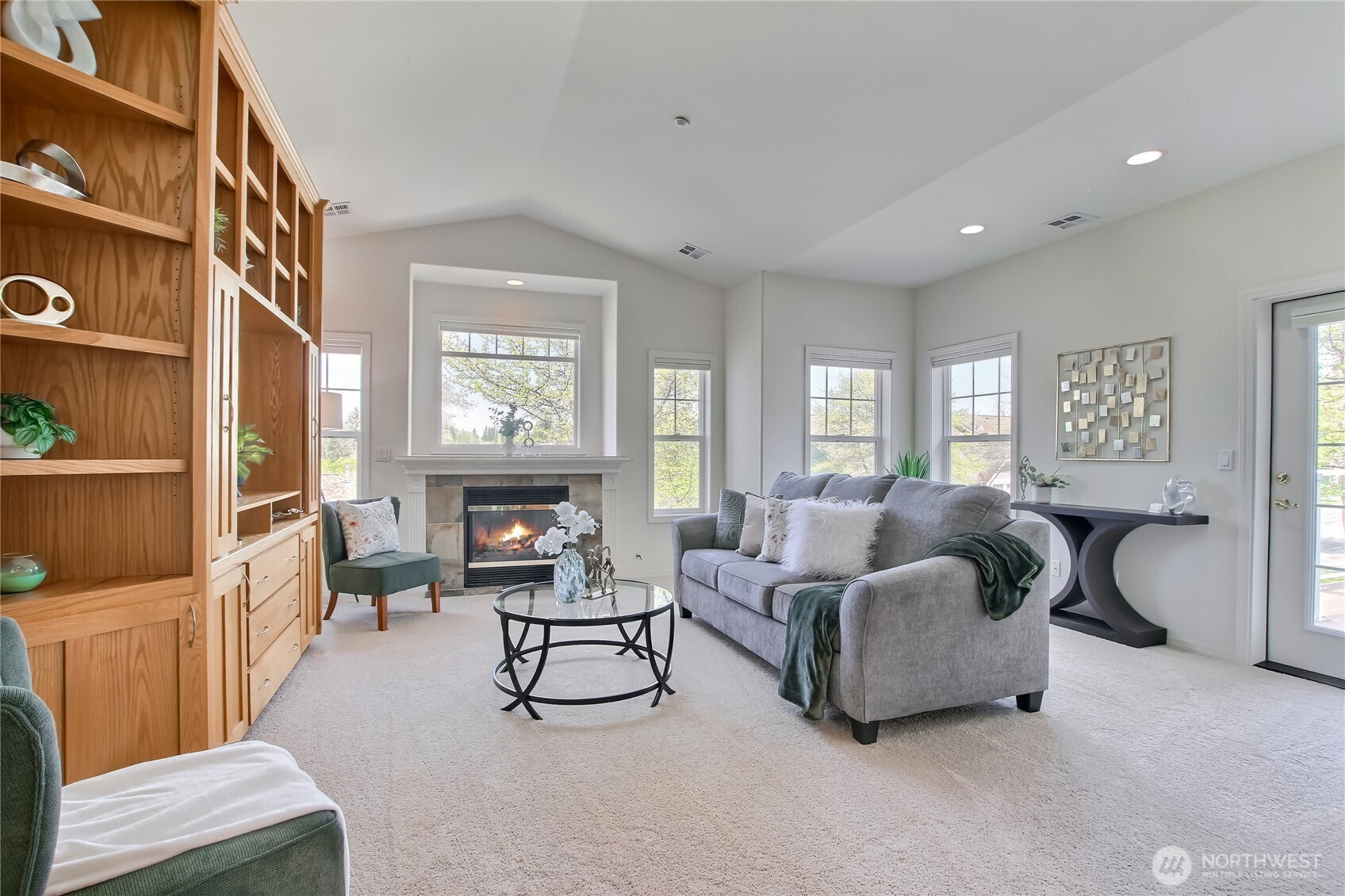Living room with gas fireplace, vaulted ceilings, and door to spacious deck.