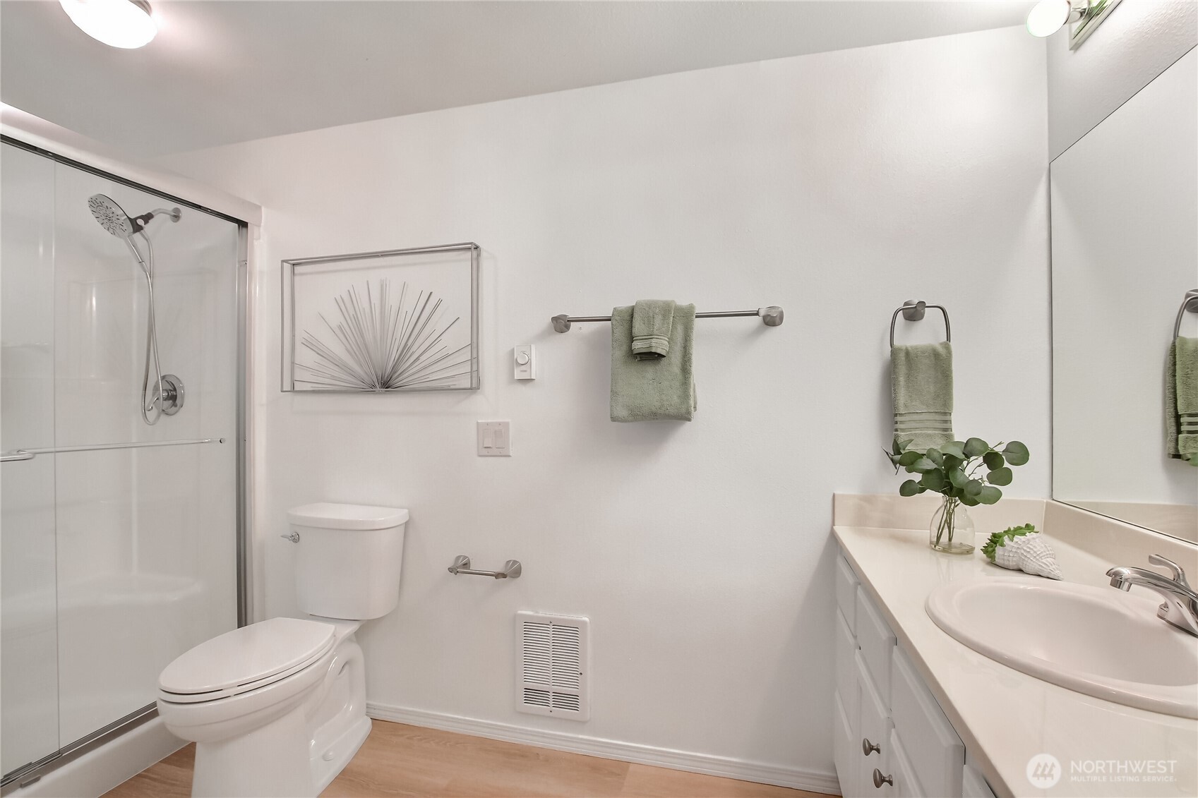 Primary bath with upgraded shower stall, glass doors, and luxury vinyl plank floors.