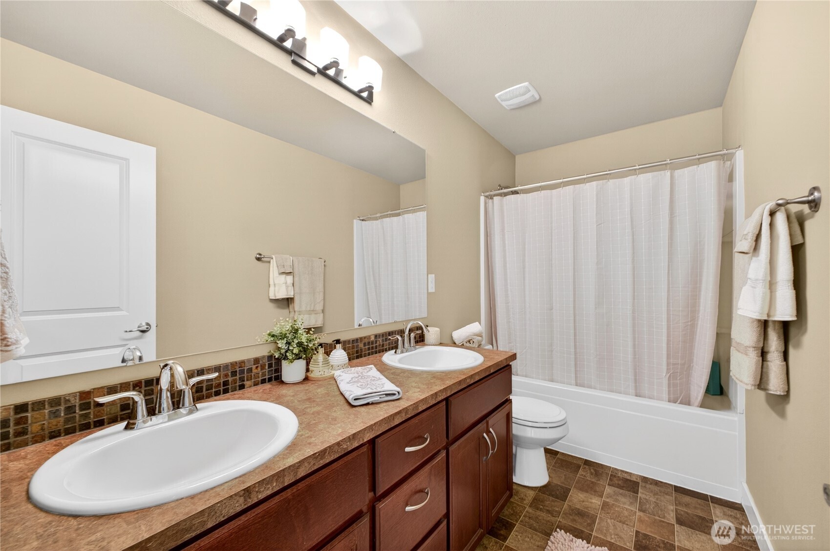Main bathroom features double sinks, tile backsplash, and generous cabinet and counter space for added convenience.