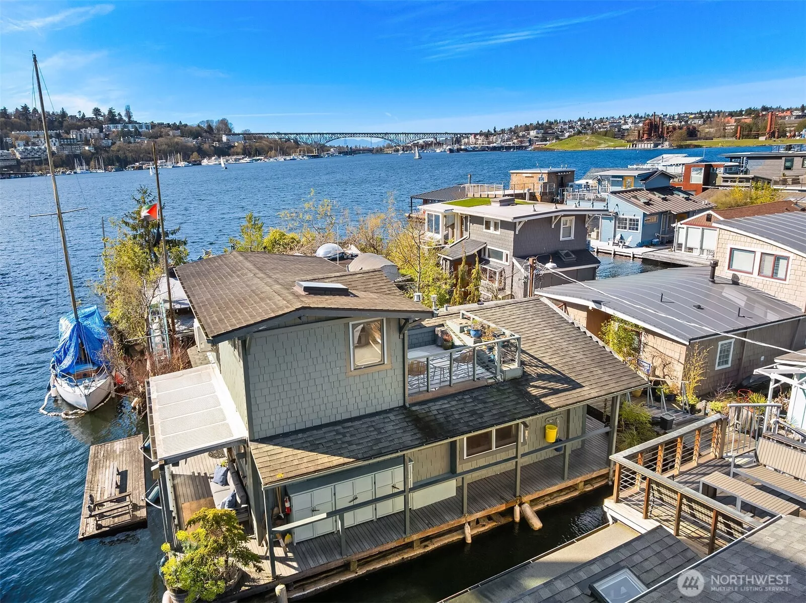 An aerial view captures the home's enviable position on Lake Union, surrounded by water, with the Aurora Bridge, Queen Anne, and the Eastlake floating home community all in view.
