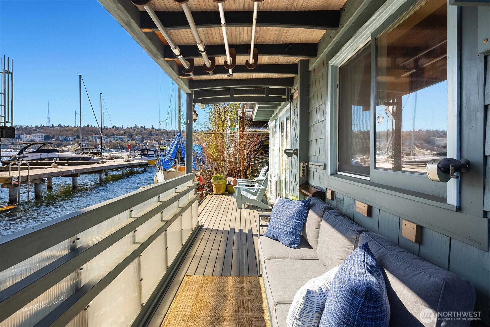 A long covered deck runs alongside the home, offering a sheltered outdoor living space with water views in any weather.