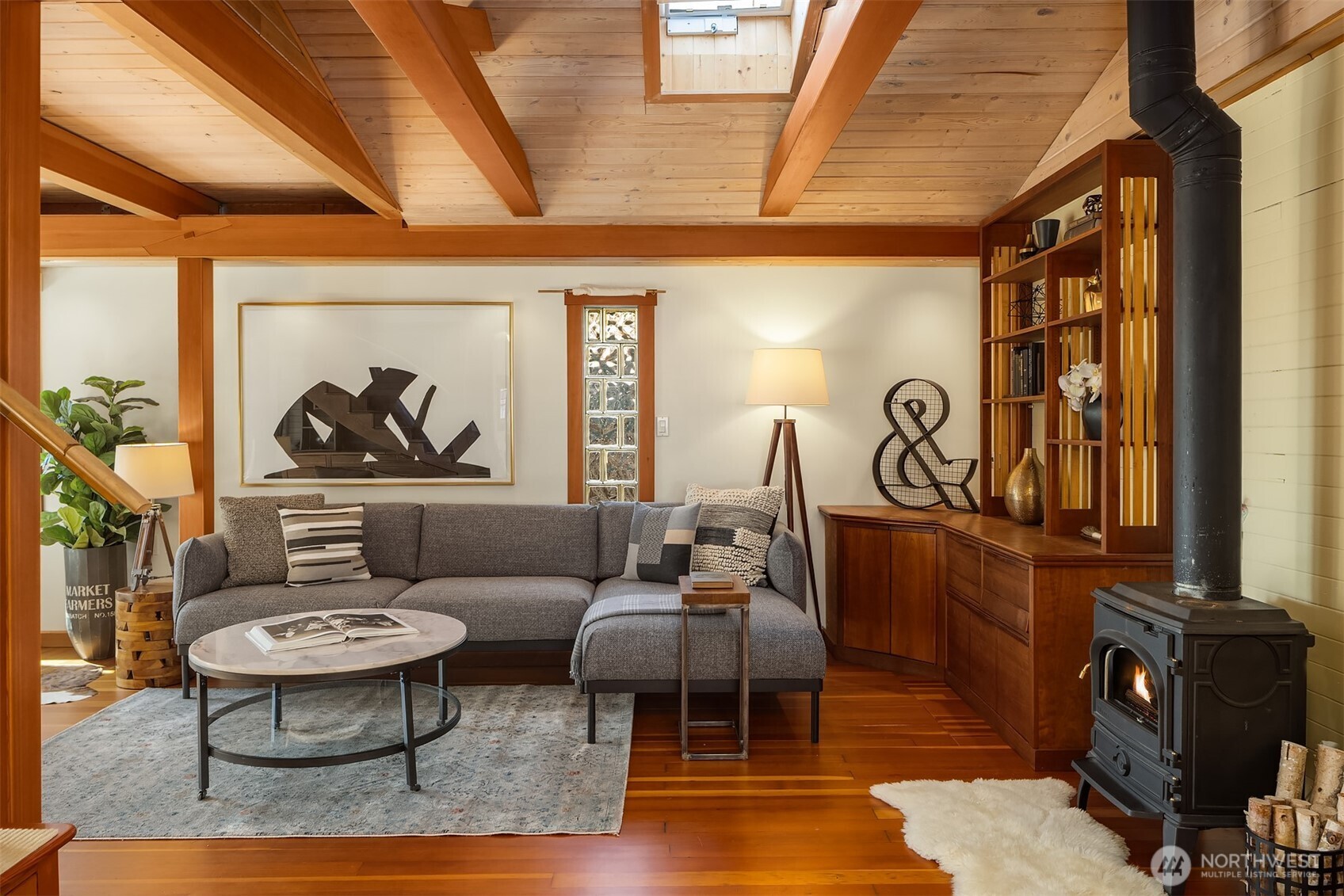 The living room's full sweep of vaulted beams, skylights, wood stove, built-ins, and gleaming hardwood floors.