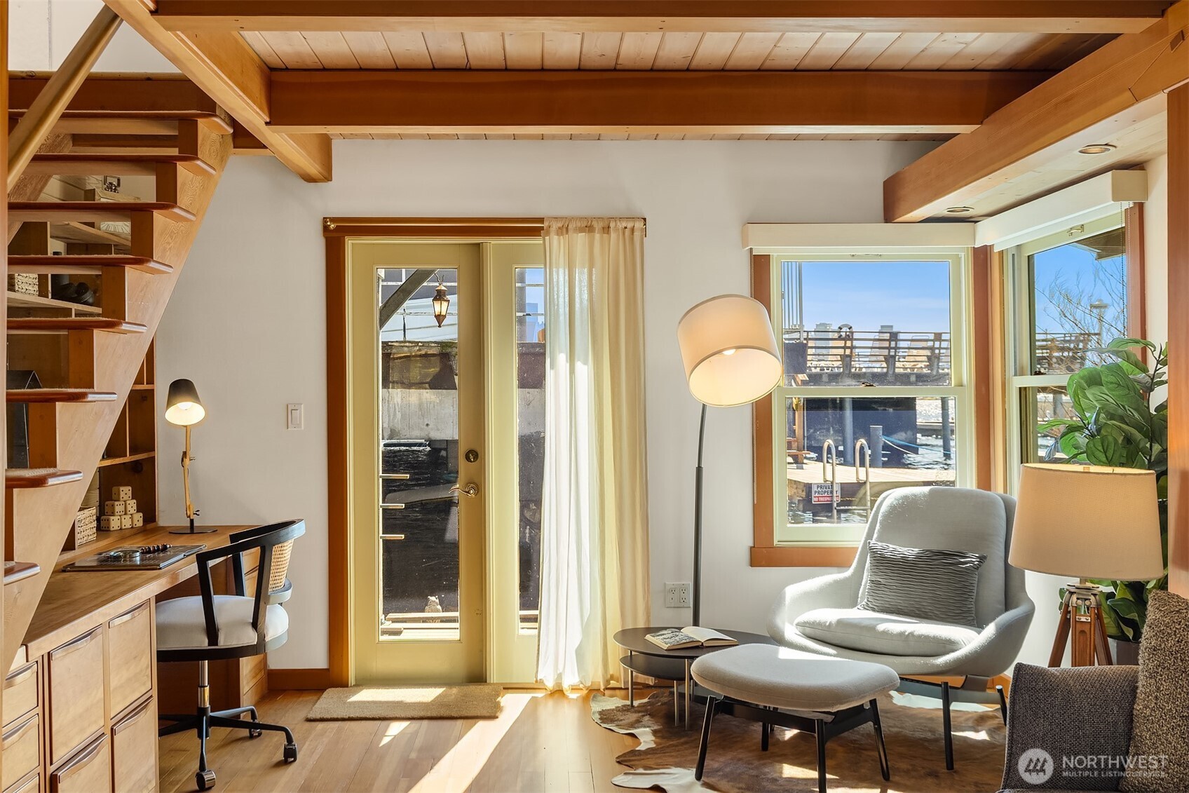 The living room's French door opens directly onto the dock, blurring the line between the warmth of the interior and the sparkling water just outside.