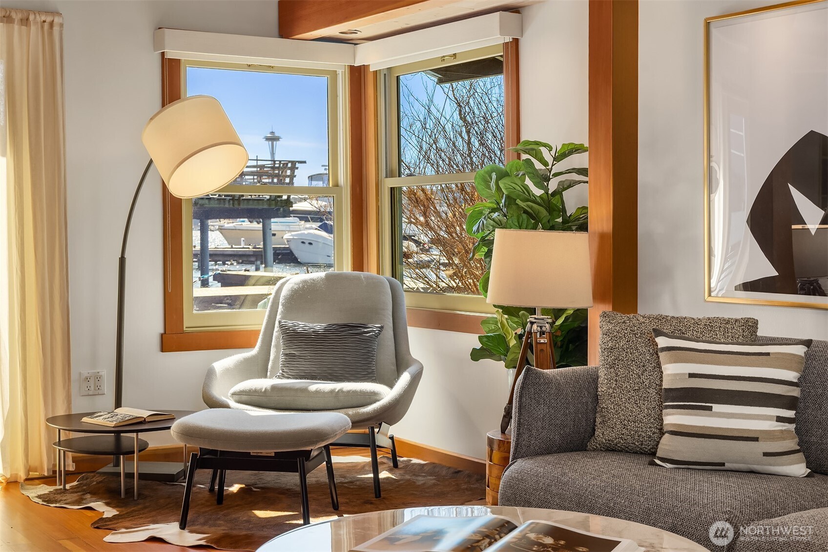 A reading chair tucked into the corner of the living room frames a marina view that includes a glimpse of the Space Needle — a daily reminder of where you are.