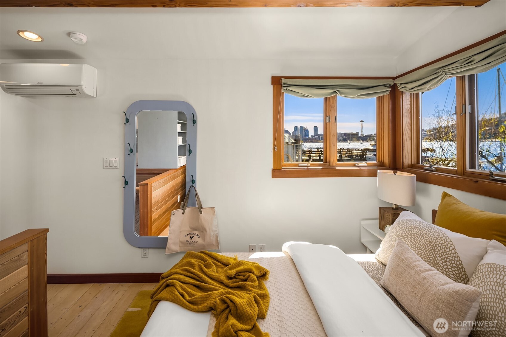 The primary bedroom's corner window frames a cinematic view: the Space Needle, the downtown Seattle skyline, and Lake Union glittering below.