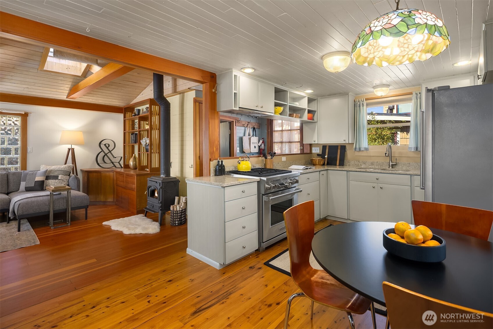 The kitchen and living room share a natural flow, anchored by a cast-iron wood stove that makes the whole main level feel warm and inviting on Pacific Northwest evenings.