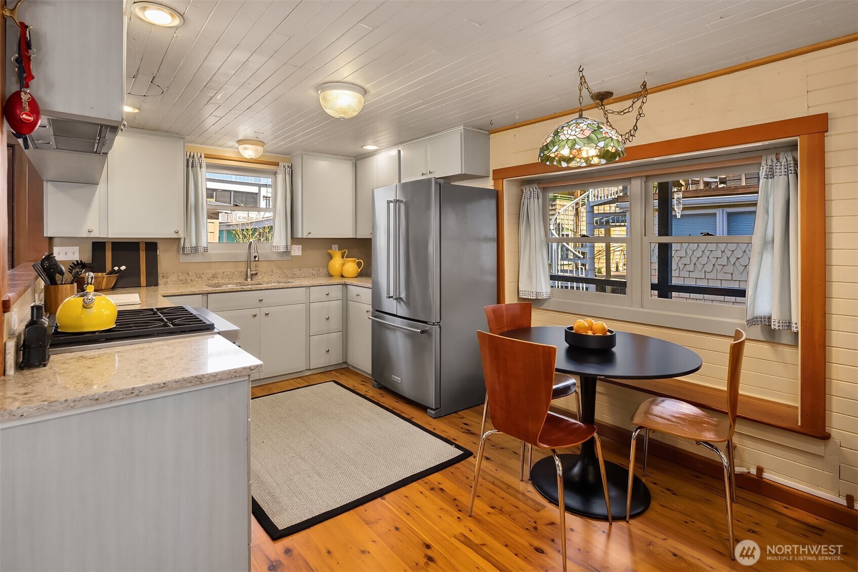 The updated kitchen combines wood cabinetry, granite countertops, and stainless appliances with the warm glow of a Tiffany pendant over the dining nook — equal parts functional and charming.