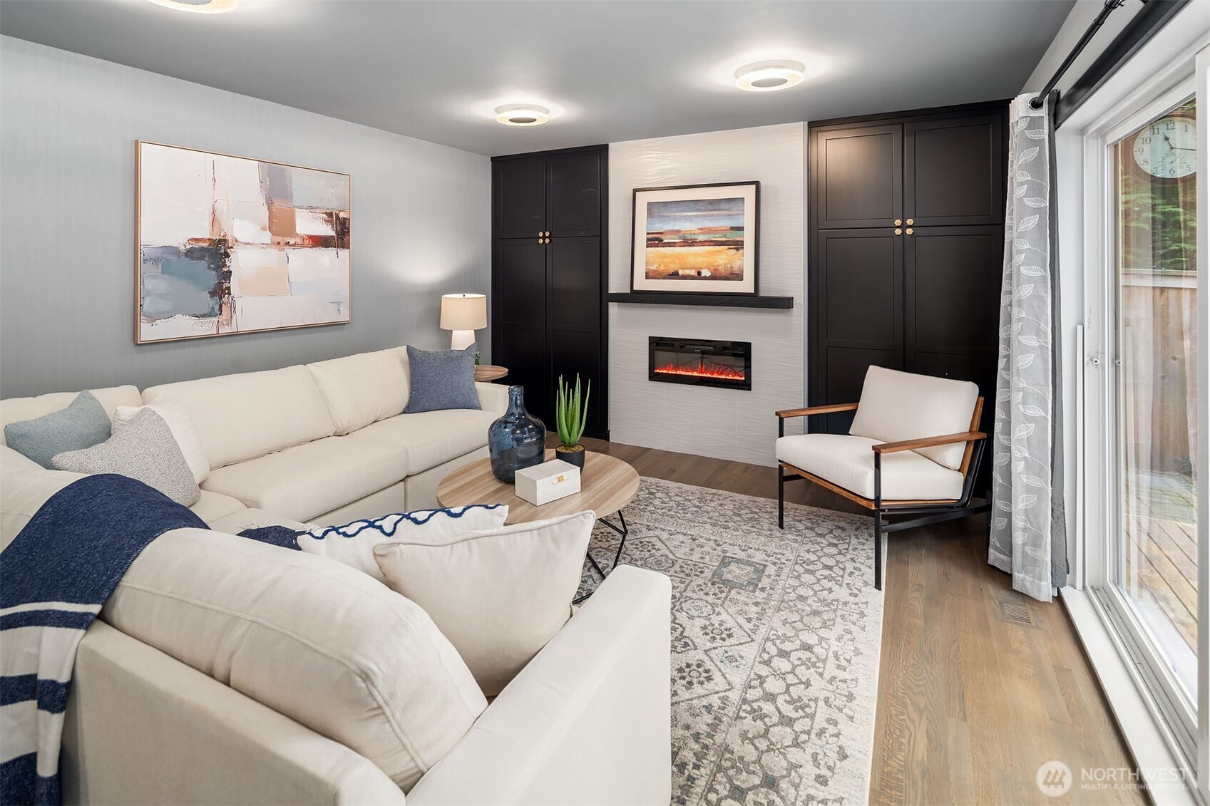 Family room off kitchen with electric fireplace, built-ins on both sides and spot for TV above mantel.