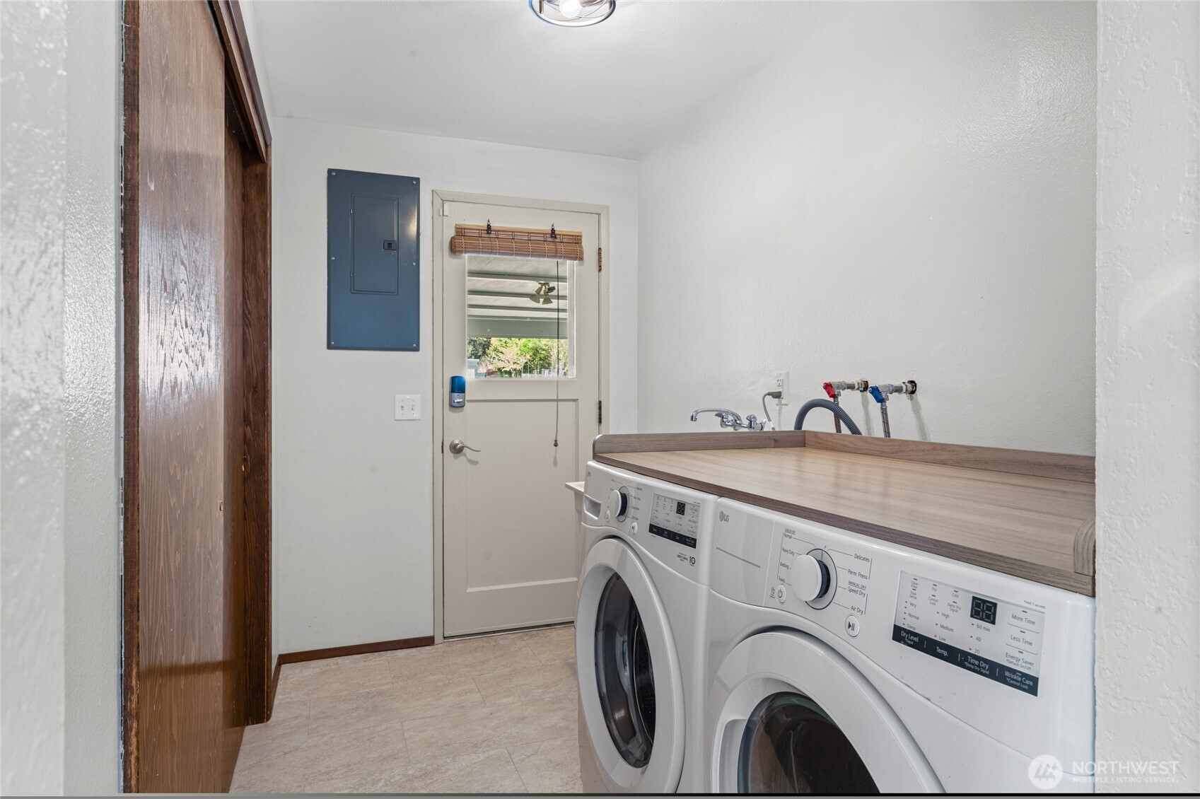 The laundry room with utility sink and wall-to-wall storage closet.   The door is the owners entry from the carport.