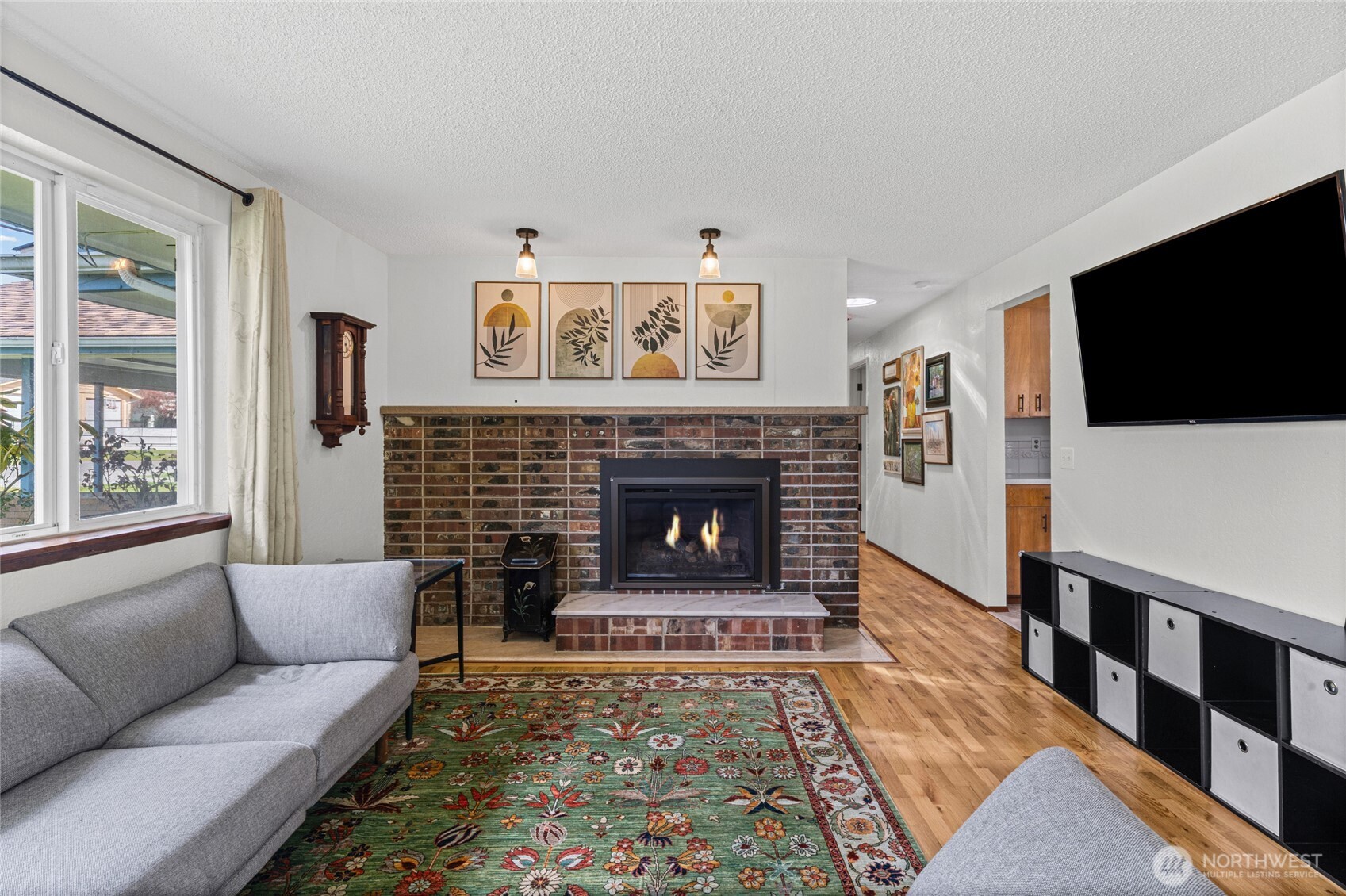 The natural gas fireplace keeps you comfortable in our cooler PNW days. Notice the stacked brick and stone hearth and the ceiling mount lights to spotlight your wall art or mantle decor.
