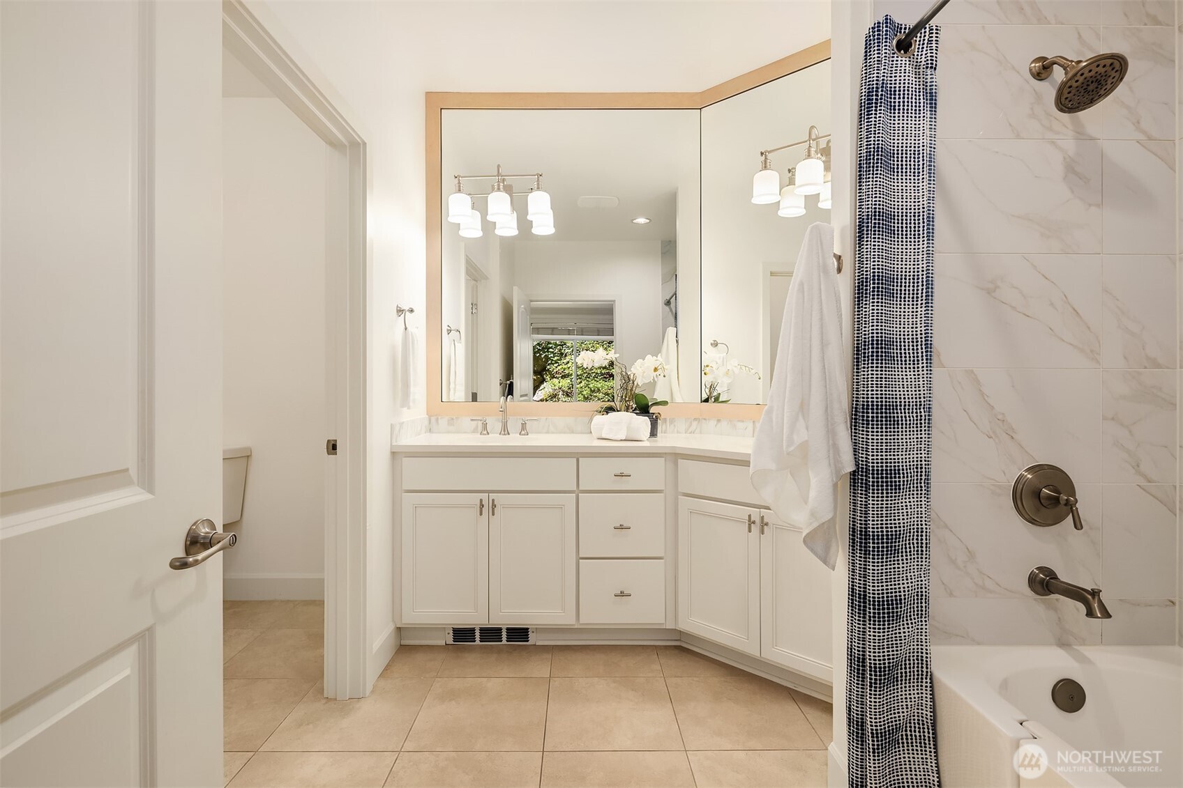 Remodeled bathroom is stylishly updated with dual vanities, sleek tile floors and generous space to move comfortably