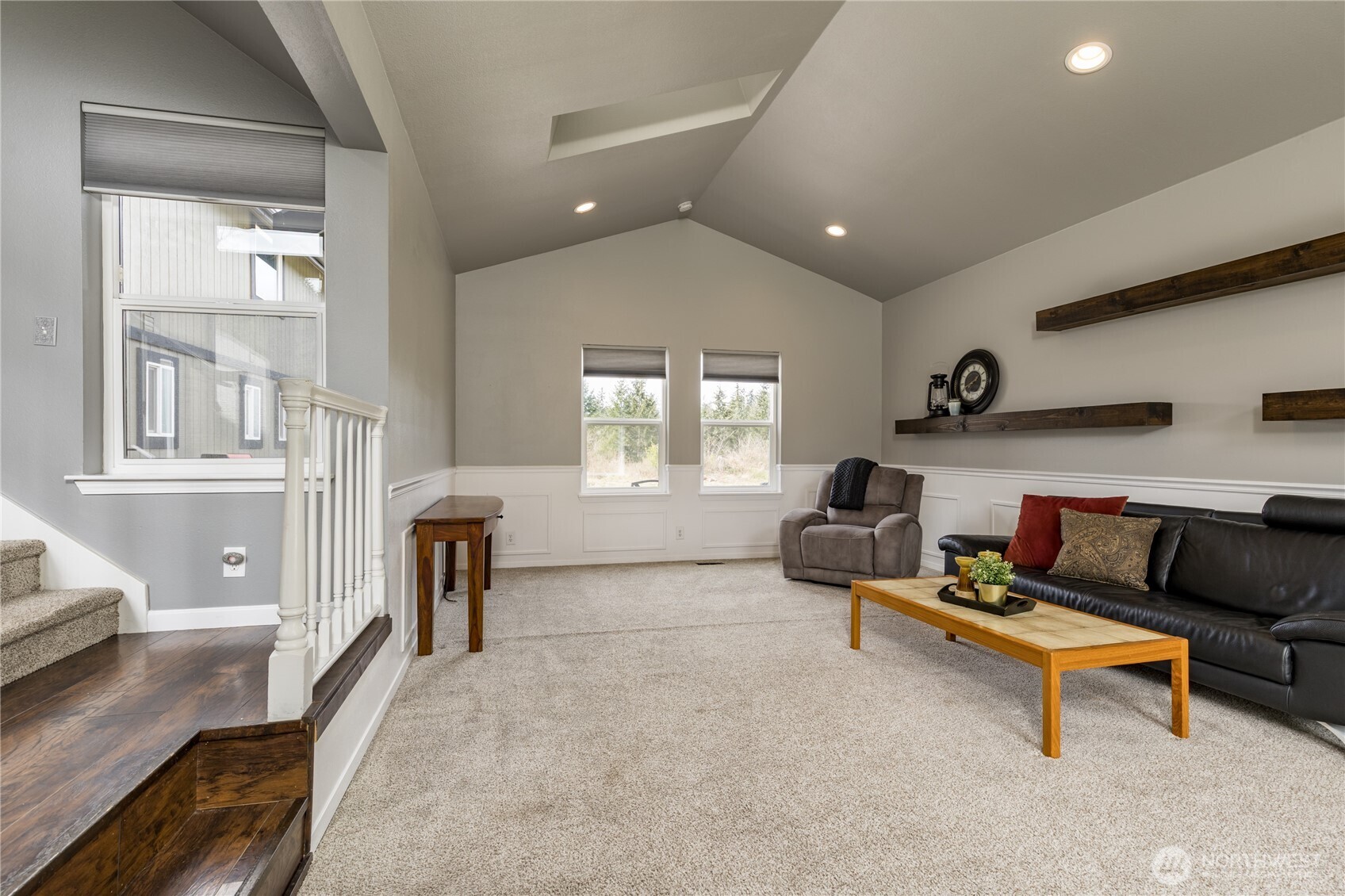 Elegant formal living room featuring soaring vaulted ceilings, classic wainscoting, and a bright skylight that bathes the space in natural light