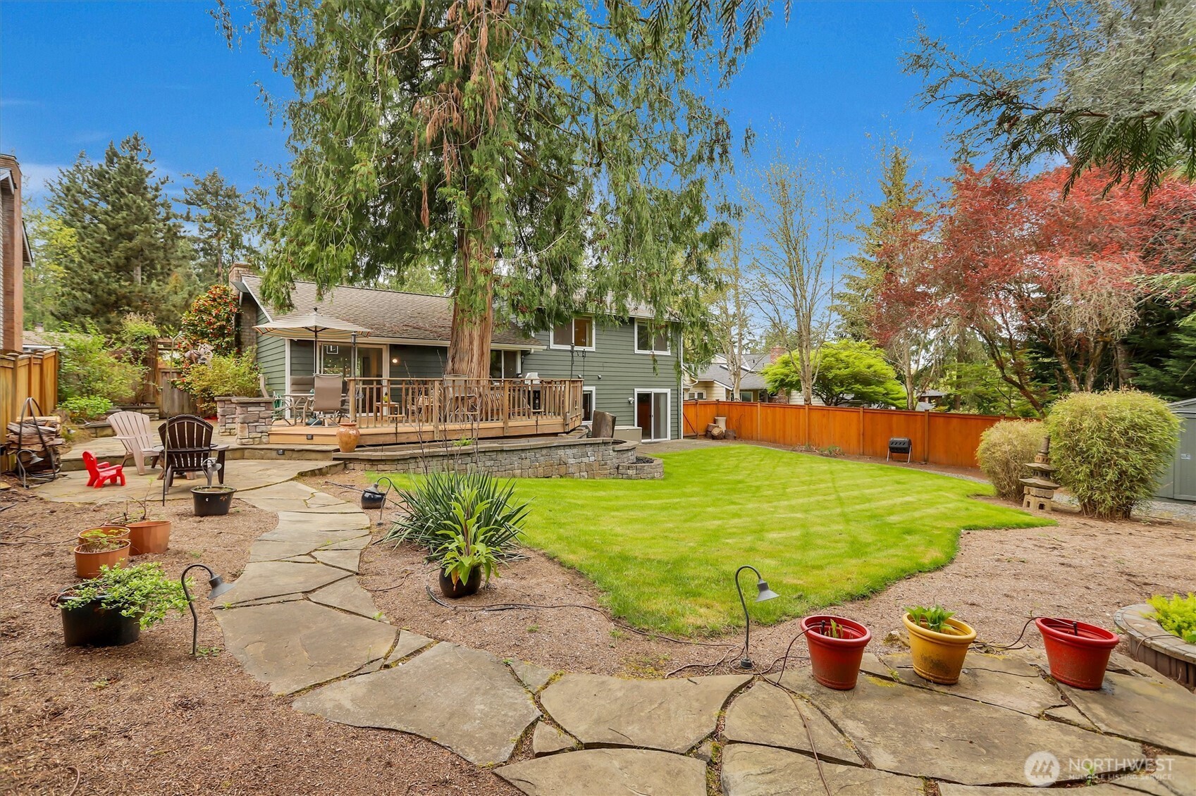 Park-like back yard with stone walkway, garden space, and water feature.
