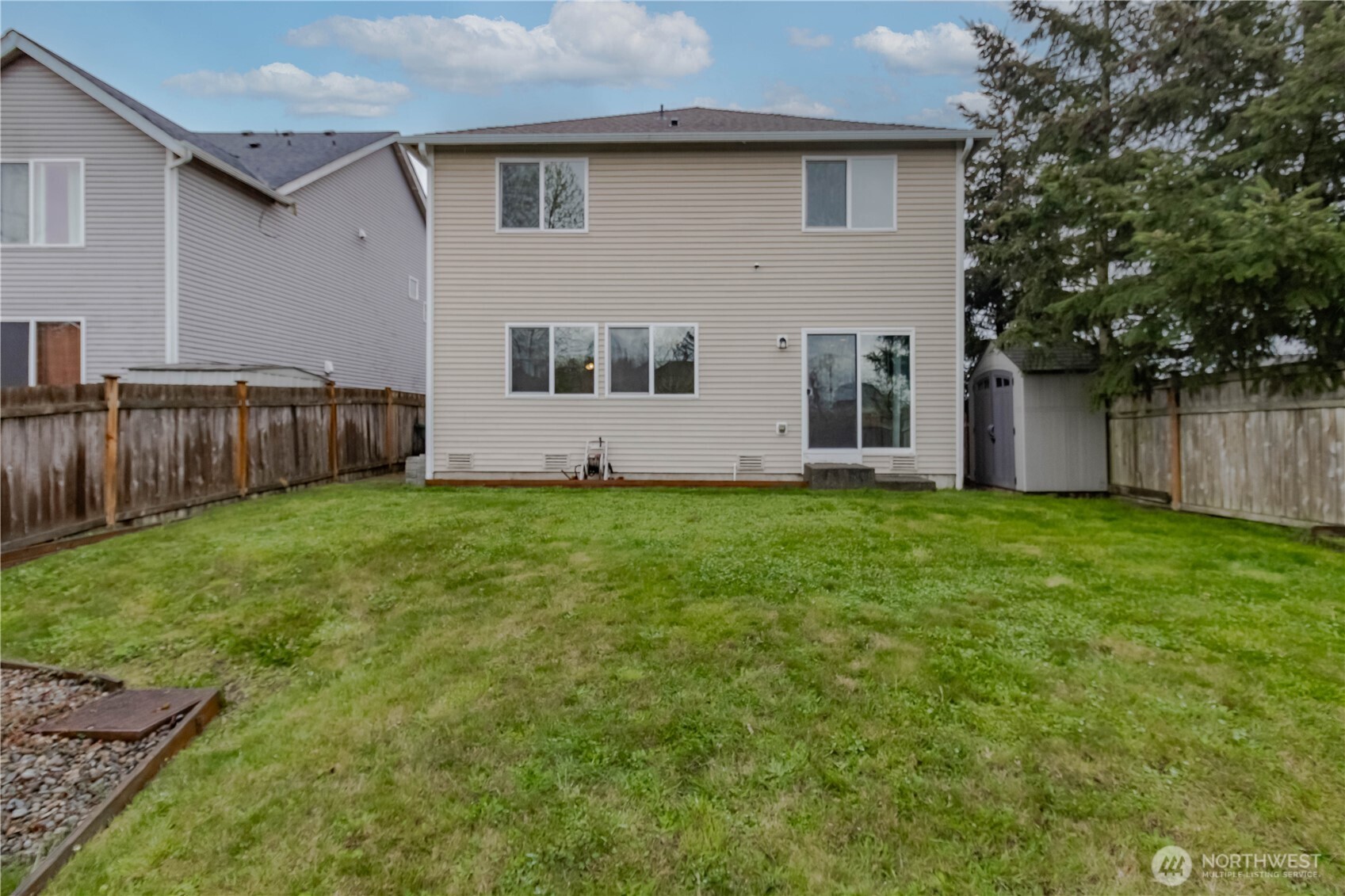 Another view of the fully fenced back yard with shed that stays