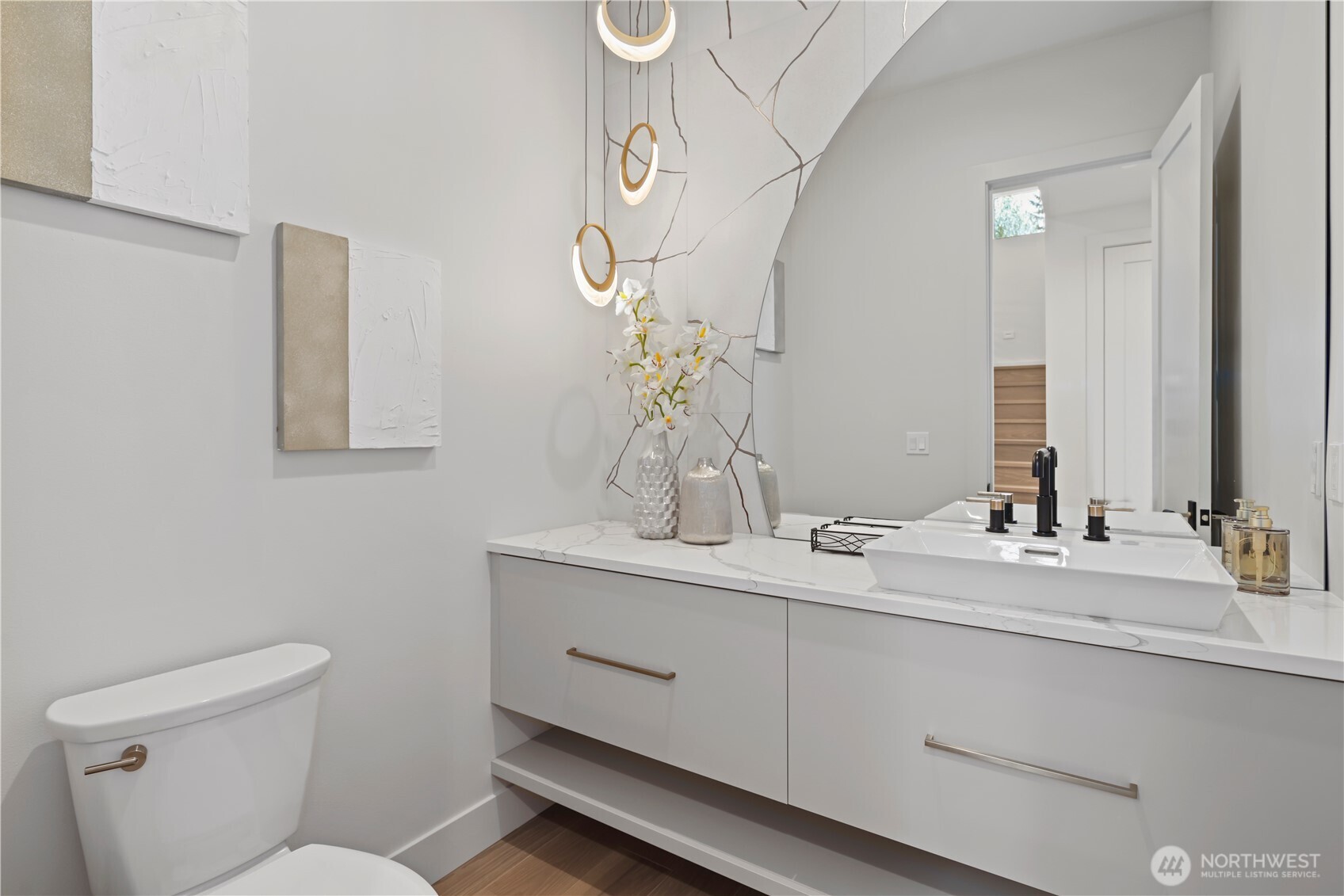 Tres chic! Main-level powder room with floating vanity, half-moon back-lit mirror, vessel sink and on-trend Alabaster and gold rimmed pedant lights.