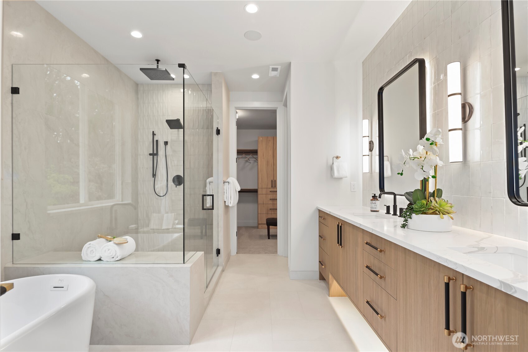 Spa-inspired bath with frameless glass-enclosed shower and full-height tile surround. Ceiling rain shower, wall rain shower head, and a handheld shower wand.