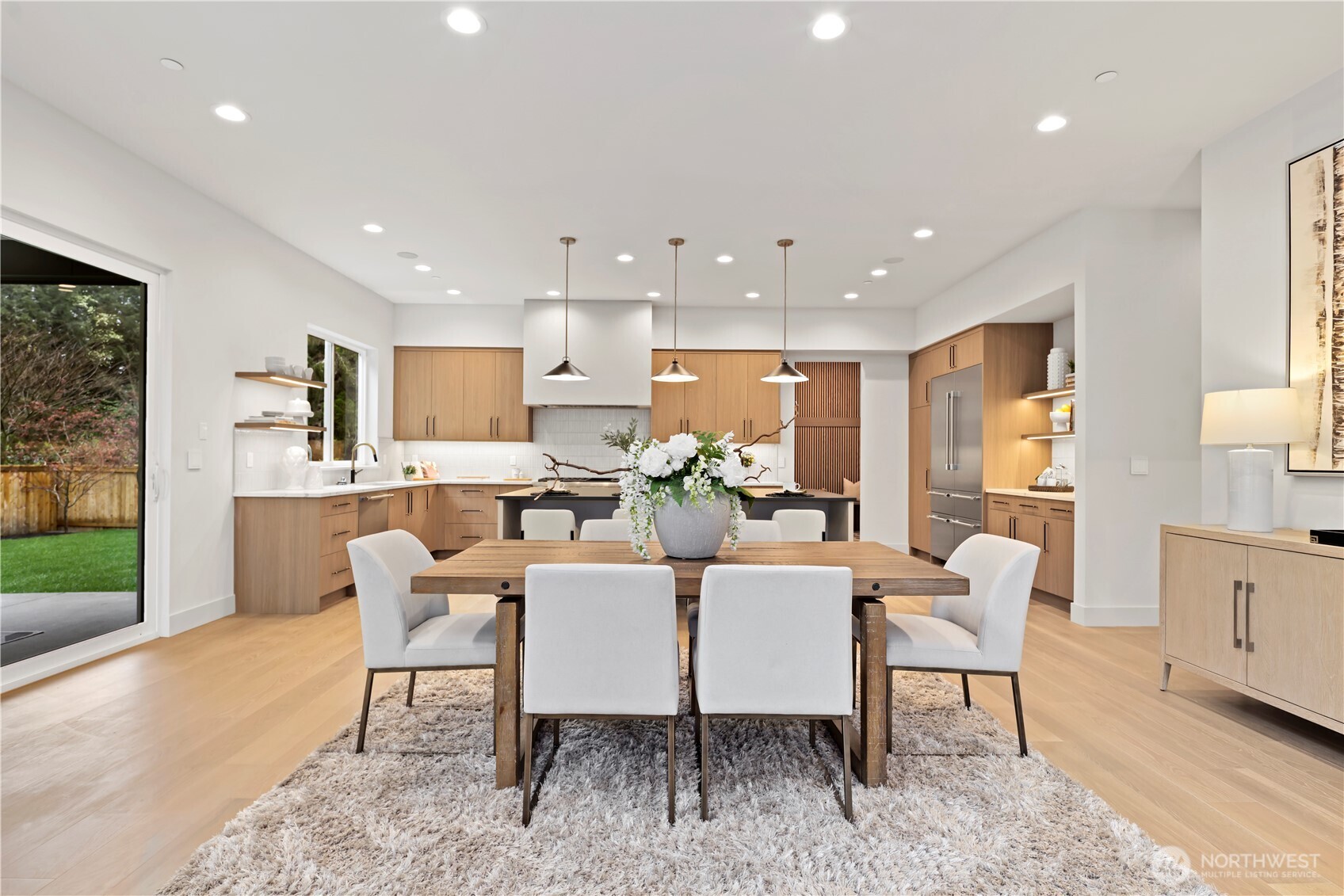 Open informal dining flows to chef’s kitchen with oversized island, warm wood cabinetry and backyard access.