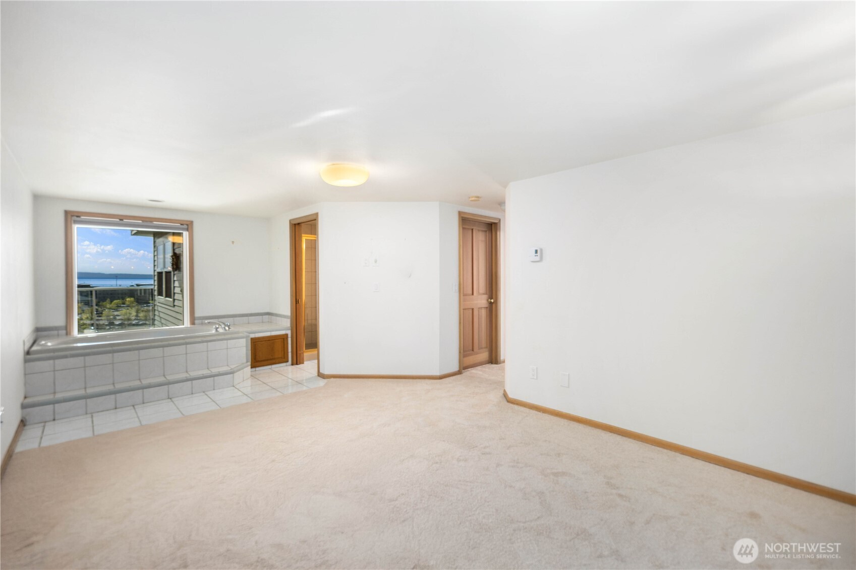 Primary Jacuzzi tub with views and privacy window