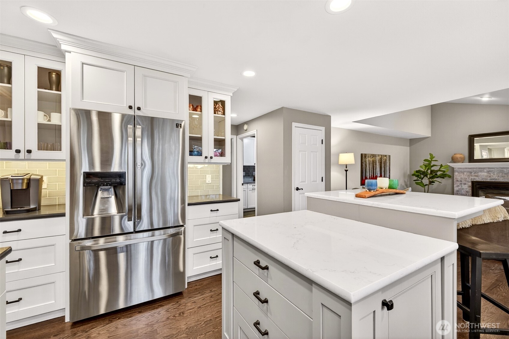 The updated kitchen showcases abundant shaker cabinetry — including glass-front display uppers — stainless appliances, subway tile backsplash, and generous counter space that makes meal prep and storage equally effortless.