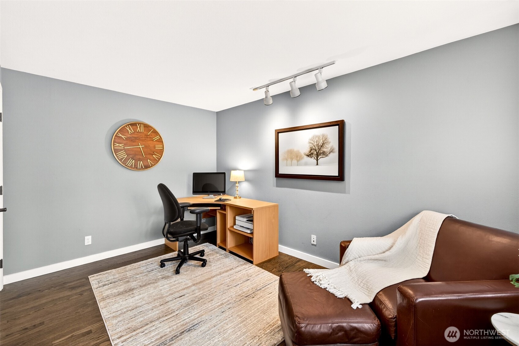 A versatile main-level room with track lighting and hardwood floors offers an ideal setup for a home office, den, or flex space — a valuable feature for today's remote and hybrid work lifestyle.