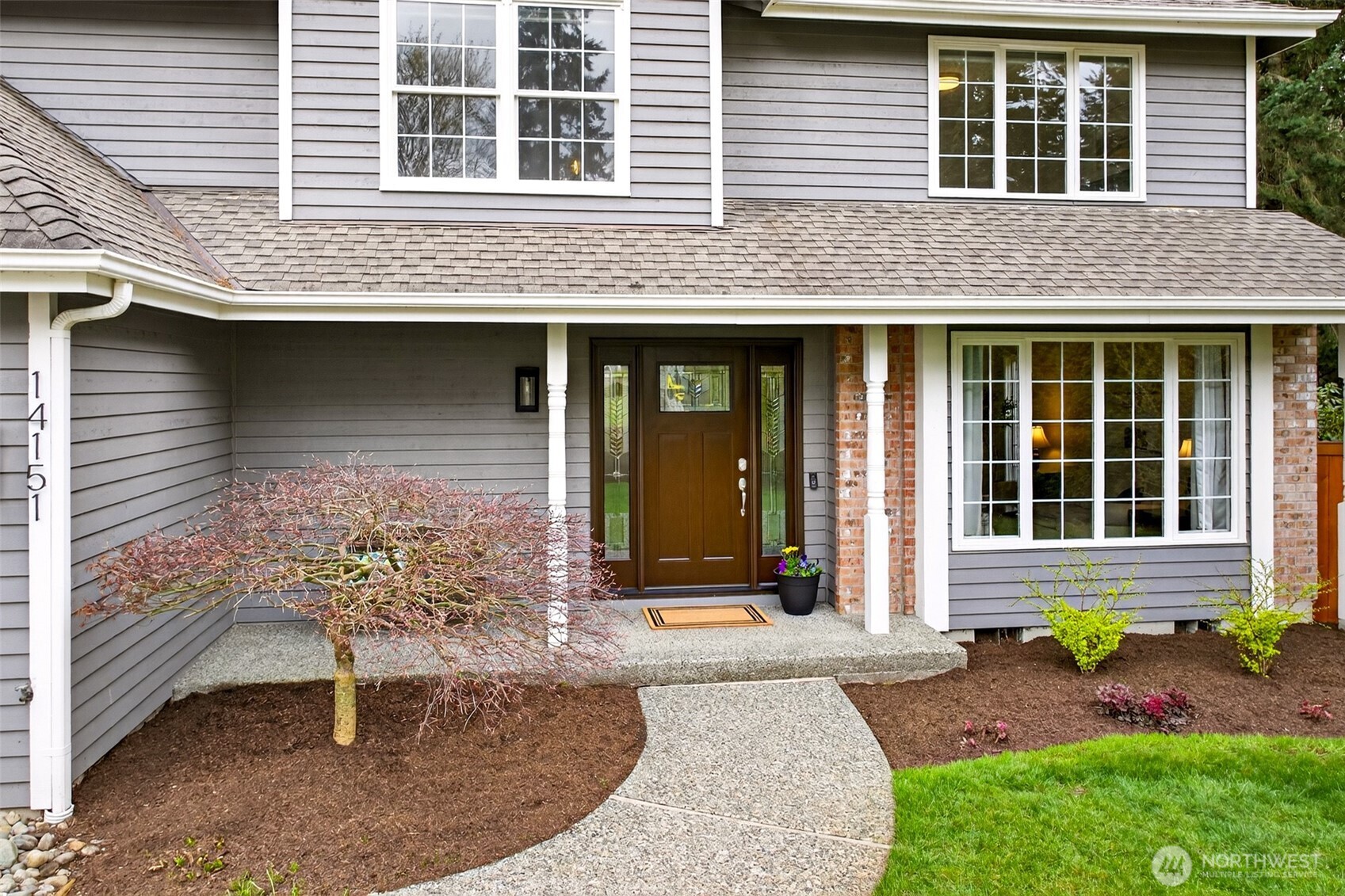 The updated front entry greets you with artisan-glass sidelights, a charming covered porch, and brick accent details — a polished arrival experience that sets the tone for everything inside.