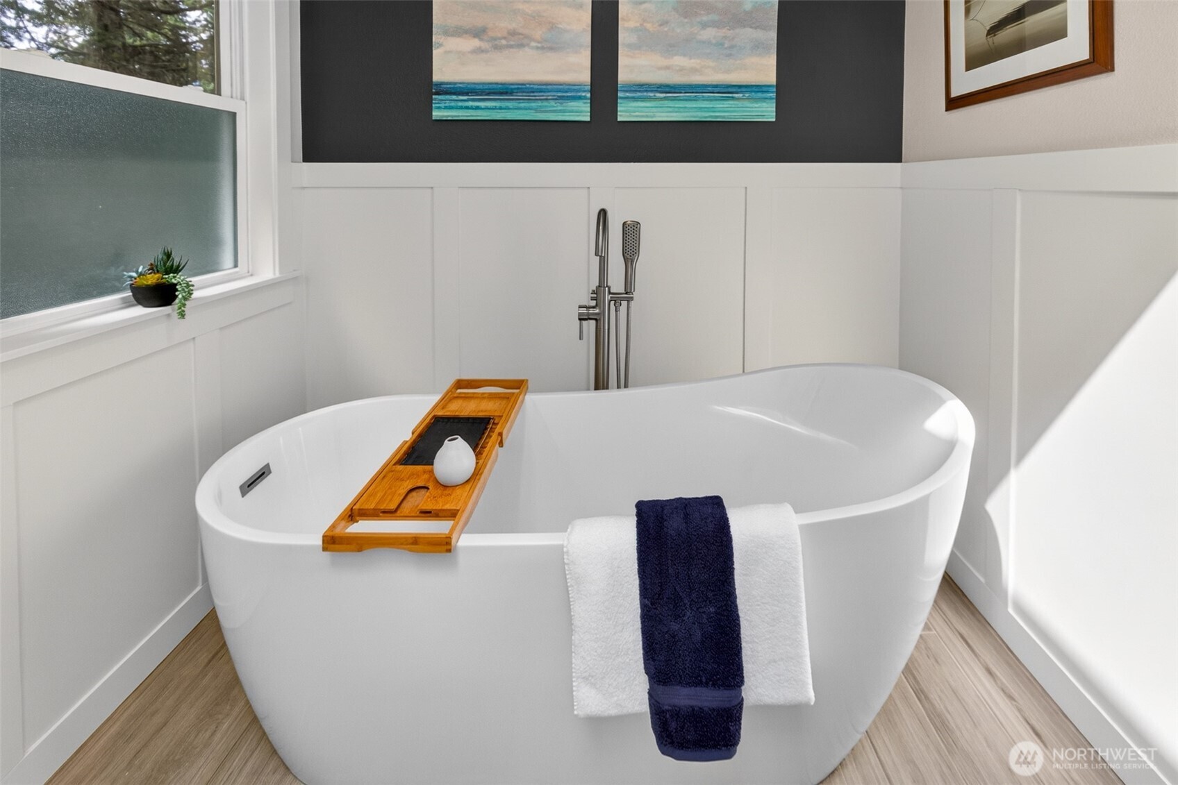 The freestanding soaking tub in the updated primary bath is the ultimate end-of-day indulgence — set beneath privacy windows and framed by crisp board-and-batten wainscoting for a clean, spa-inspired aesthetic.