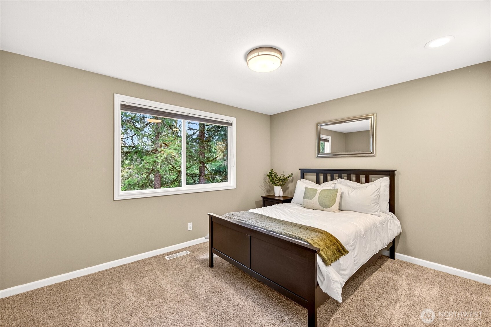 A secondary bedroom with plush carpet, a treetop window view, and a tranquil, private feel — ideal as a guest room, second bedroom, or a quiet upstairs retreat.