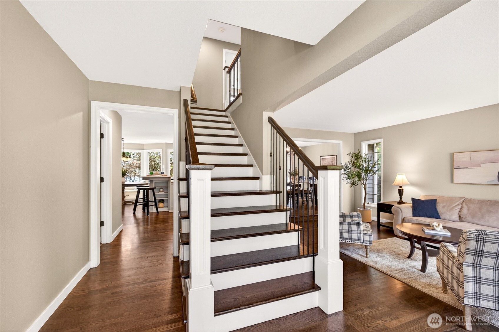 The open entry foyer with its striking staircase — featuring dark hardwood treads and iron balusters — creates an immediate sense of architectural character, with views flowing naturally toward the living and dining areas.