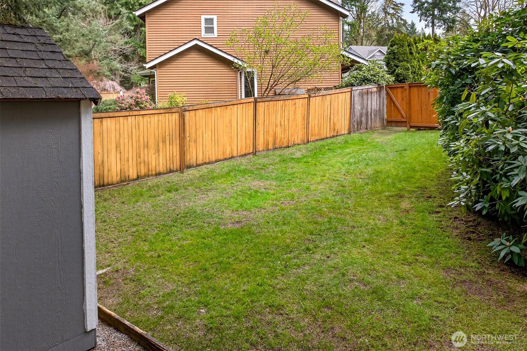 A fully fenced side yard with lawn and mature plantings provides valuable additional outdoor space — ideal for a garden, play area, or simply the extra room and privacy that's increasingly hard to find on the Eastside.
