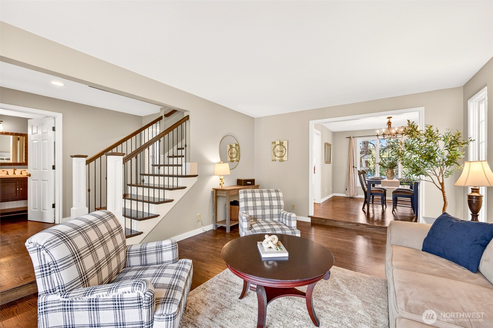 The generously sized living room offers a relaxed, connected flow between the entry, dining room, and main level powder room — a versatile space designed for how people actually live.