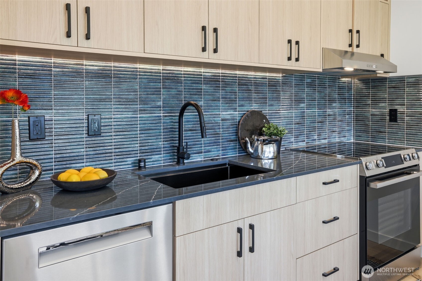 Designer kitchen with quartz countertops, custom cabinetry, stainless steel appliances, tile backsplash, and abundant storage.