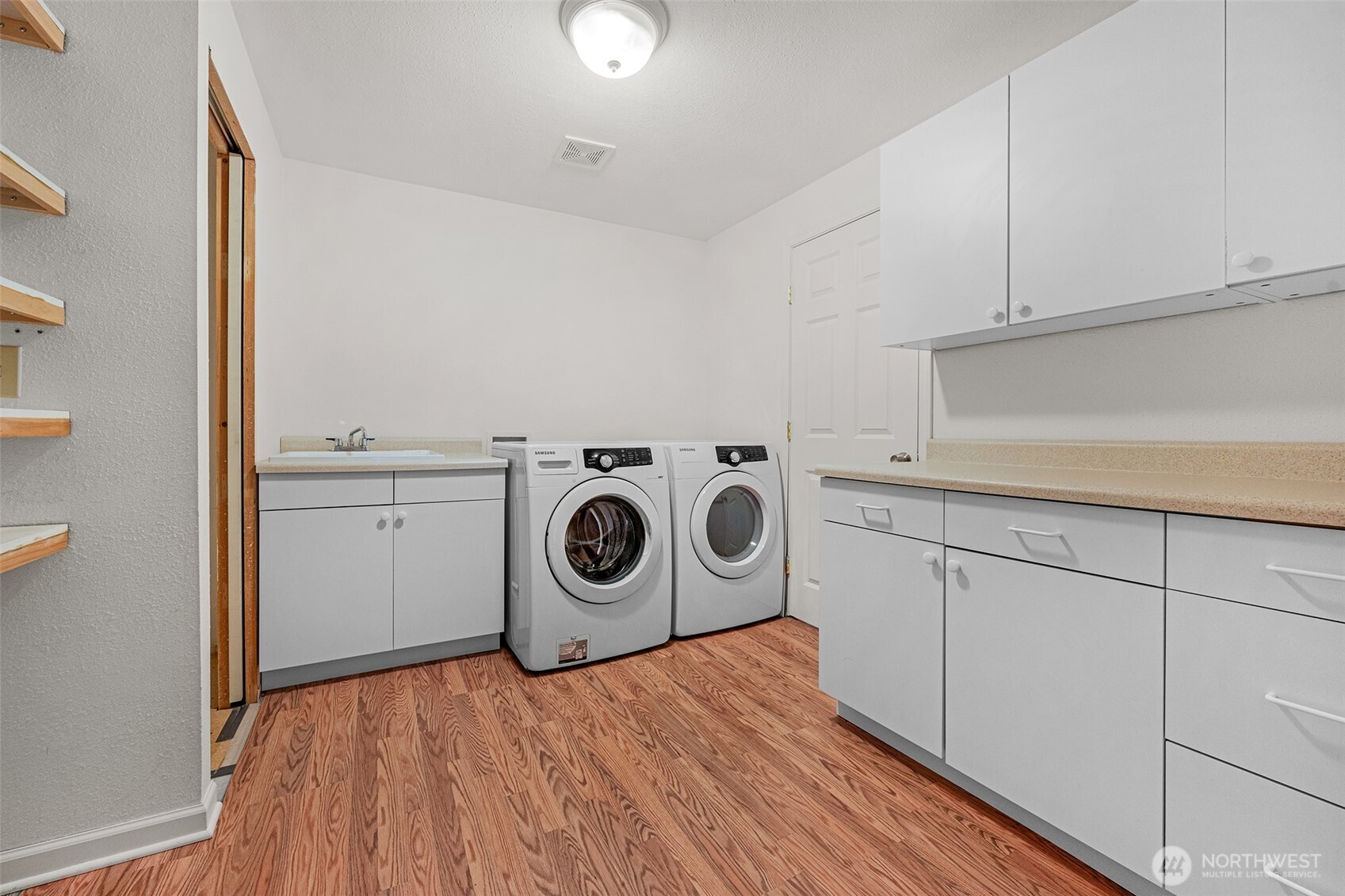 Spacious laundry room with a deep sink and plenty of cabinets and counter space. Newer washer and dryer are included.