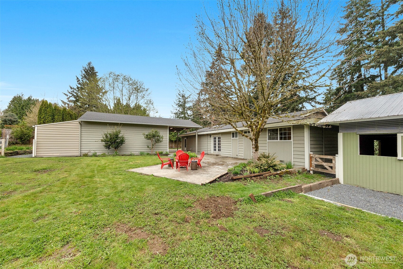 View of back yard showing the patio,barn, main house and garage/shop.