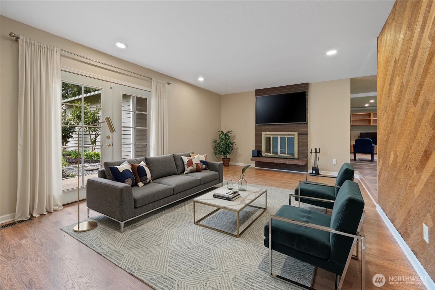 Spacious living room with wood-burning fireplace and French doors leading to the patio. (digitally staged)