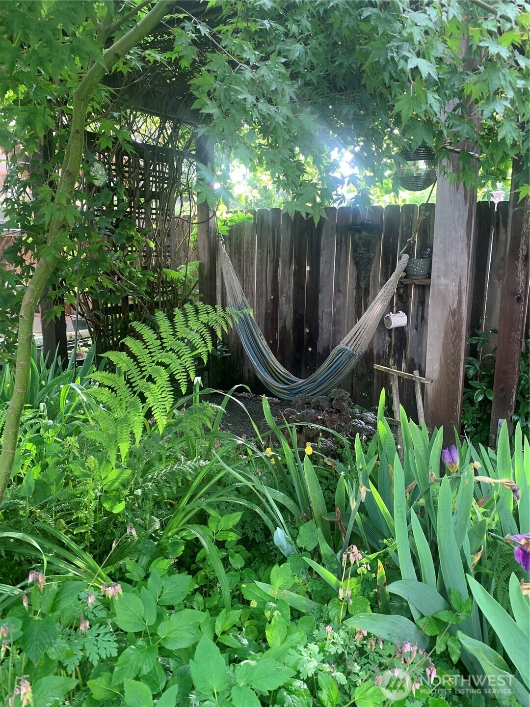 Adjacent to the greenhouse, a large arbor features built-in eye-bolt hooks for hammocks, creating an ideal space for relaxing afternoons