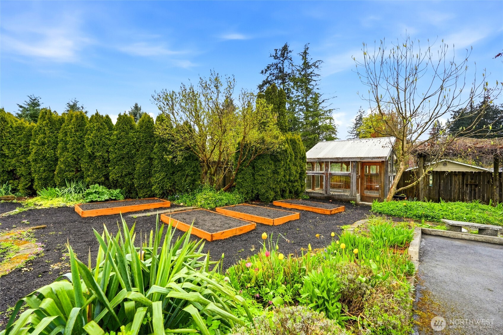 With two greenhouses, wisteria-draped arches covered in fragrant honeysuckle, and a mix of sun and shade growing areas, it is ideally suited for both ornamental and food production
