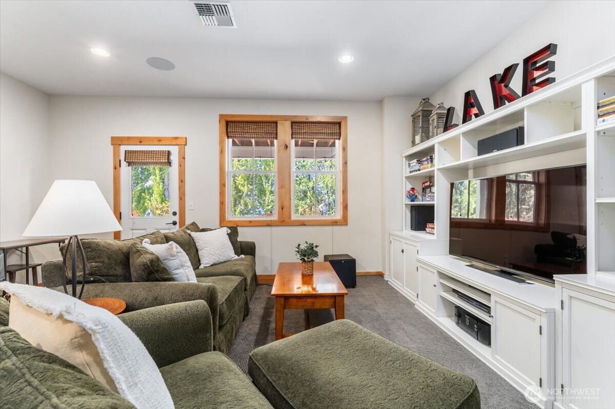 View 1 of lower level bonus/media room with doors opening to the lower level outdoor living area.