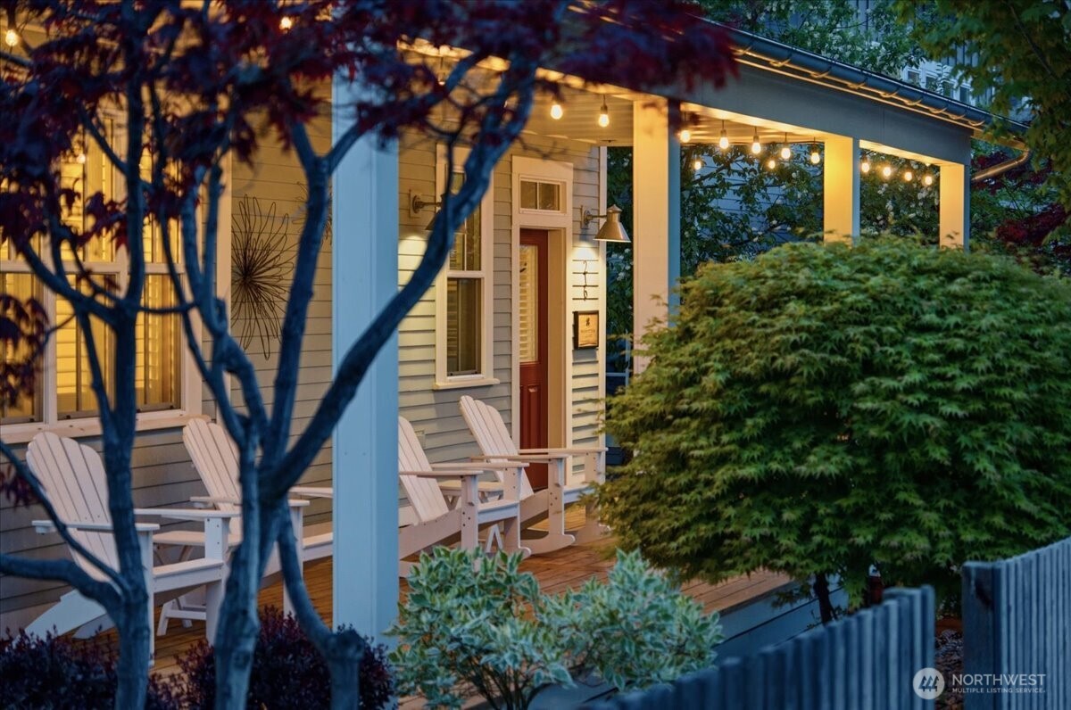 Exterior twilight view of home with classic covered front porch and mature landscaping.