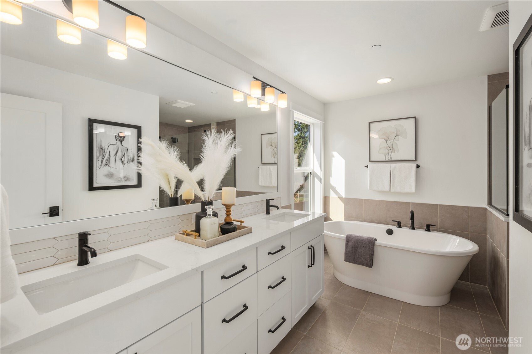 Primary Bath:  The primary bath showcases a long dual-sink vanity with quartz counters, modern lighting, and warm tile floors that contribute to a spa-like atmosphere. A soaking tub sits beside a large window, inviting natural light while maintaining privacy. Situated within Bothell’s Canyon Park area, this serene bath offers a relaxing retreat close to everyday conveniences, trails, and community amenities. With abundant counter space, matte black fixtures, and thoughtful design details, the space feels both luxurious and highly functional.    These photos are from Lot 5 at Gooden Hollow, the community model. The home listed will have changes, so all photos, renderings, site maps, and floorplans are for visualization purposes only. Plans, colors, building orientation, finishes, home outlook, and other details can and WILL vary.