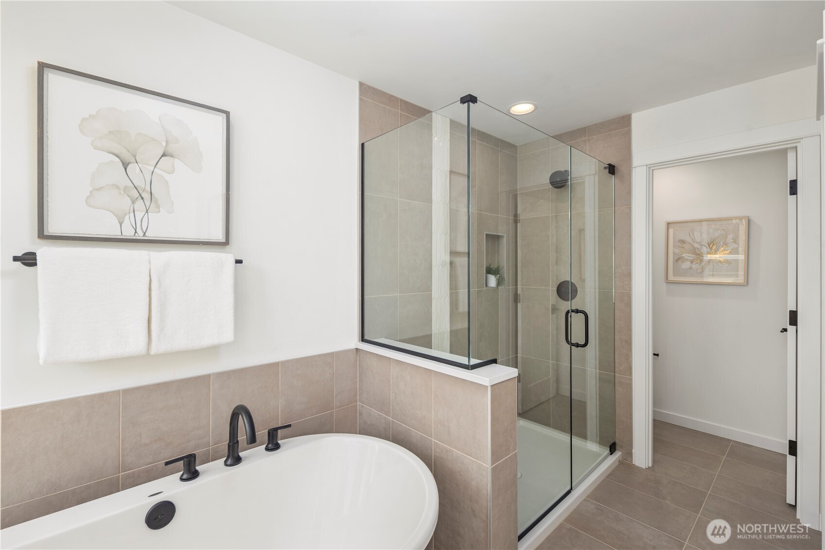 Primary Bath – Tub & Shower:  This angle highlights the pairing of a freestanding soaking tub with a spacious glass-enclosed shower, creating a balanced mix of relaxation and efficiency. The neutral tile palette adds warmth and continuity throughout the room. Located in Bothell’s Canyon Park micro-area, the primary bath complements a lifestyle surrounded by parks, everyday amenities, and quick access to major commuting routes. Its clean, modern finishes elevate daily routines with a quiet sense of luxury.    These photos are from Lot 5 at Gooden Hollow, the community model. The home listed will have changes, so all photos, renderings, site maps, and floorplans are for visualization purposes only. Plans, colors, building orientation, finishes, home outlook, and other details can and WILL vary.