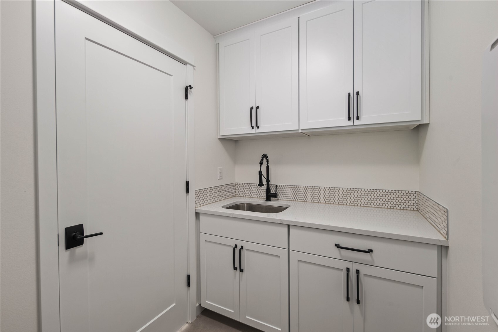 Laundry Room (Sink + Cabinetry Wall):  A secondary laundry workspace features expansive countertop space, deep utility sink, and full-height cabinetry for storing essentials. This thoughtful layout supports multitasking—folding, soaking, sorting—while keeping the rest of the home clutter-free. Positioned in Bothell’s Canyon Park neighborhood, it brings a practical rhythm to daily living near local shops, trails, and commuter routes. The stylish tile backsplash adds subtle texture and elevates the room with a polished, modern touch.    These photos are from Lot 5 at Gooden Hollow, the community model. The home listed will have changes, so all photos, renderings, site maps, and floorplans are for visualization purposes only. Plans, colors, building orientation, finishes, home outlook, and other details can and WILL vary.