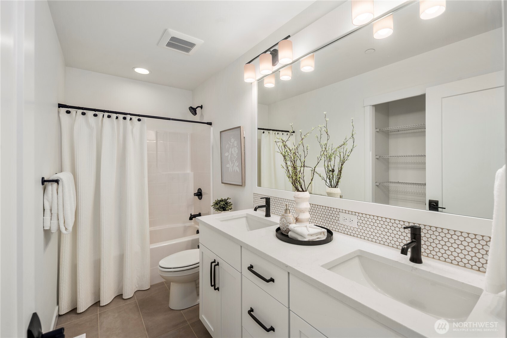 Upper-Level Full Bathroom:  This well-appointed full bath blends modern styling with everyday functionality, featuring a long quartz-topped dual-sink vanity, matte black hardware, and a full-height mirror that brightens the space. The wide layout supports easy morning routines, while the tiled flooring and thoughtful storage keep the room feeling tidy and efficient. Located in the heart of Bothell’s Canyon Park area, the home places you minutes from local trails, cafés, and schools while maintaining excellent access to I-405. Subtle details—like the penny-tile backsplash and streamlined lighting—add a polished, elevated feel that complements the rest of the home.    These photos are from Lot 5 at Gooden Hollow, the community model. The home listed will have changes, so all photos, renderings, site maps, and floorplans are for visualization purposes only. Plans, colors, building orientation, finishes, home outlook, and other details can and WILL vary.