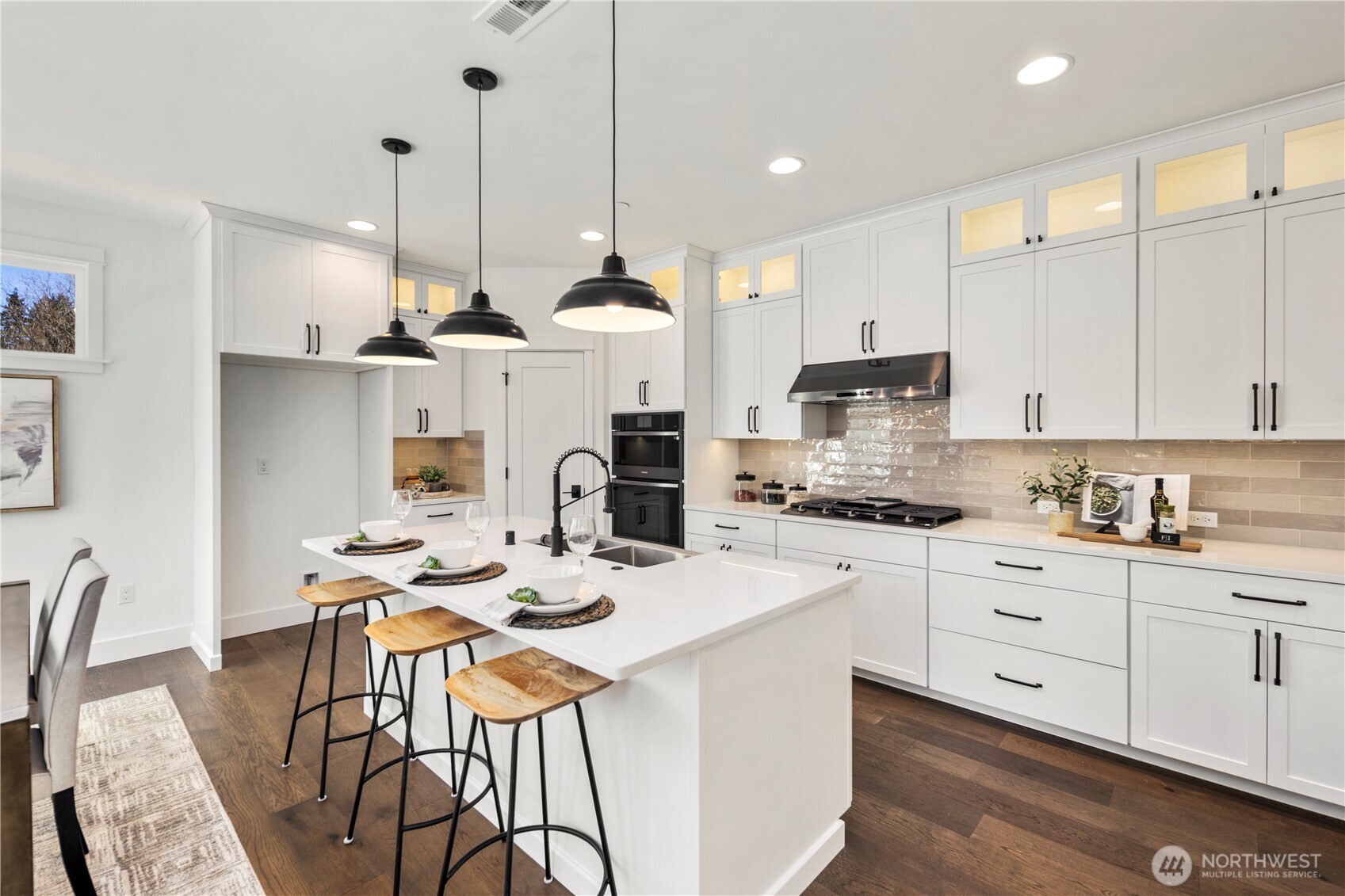 Kitchen & Dining Overview:  This combined kitchen and dining area is framed by expansive windows and sliding glass doors that bring in soft natural light and connect the interior to the private backyard. The generous layout allows for a full-size dining table while maintaining clear sightlines to the kitchen and great room. Nestled within Bothell’s Canyon Park area, the space offers a convenient balance between neighborhood living, commuter access, and the outdoor recreation that defines the PNW lifestyle. Its clean lines, warm flooring, and contemporary lighting create a welcoming setting for gatherings of all sizes.    These photos are from Lot 5 at Gooden Hollow, the community model. The home listed will have changes, so all photos, renderings, site maps, and floorplans are for visualization purposes only. Plans, colors, building orientation, finishes, home outlook, and other details can and WILL vary.