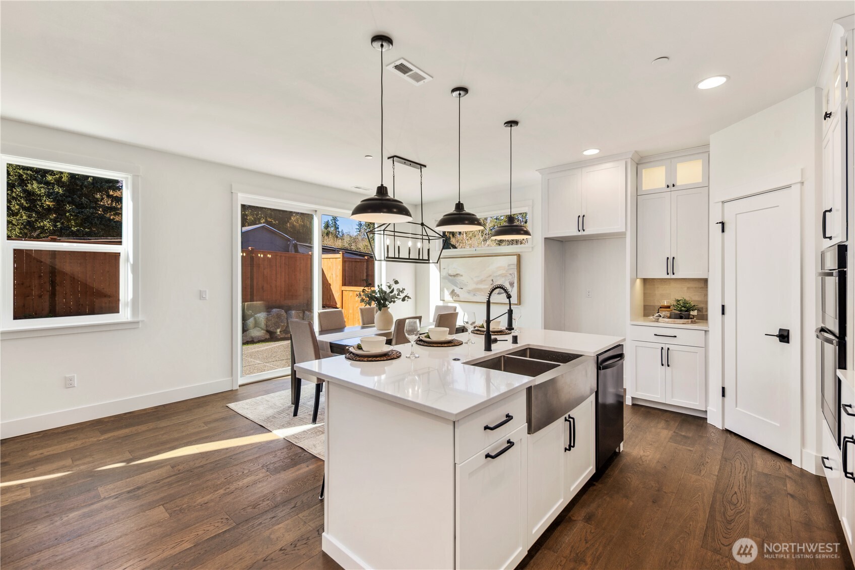 Dining Area:  This airy dining space is framed by wide-plank flooring and anchored by a sculptural modern chandelier that adds definition without overwhelming the openness. The room’s proximity to the kitchen and backyard supports easy transitions between weeknight meals, gathering, and indoor–outdoor entertaining. Situated in Bothell’s Canyon Park micro-area, the home offers quick access to nearby parks, trails, and everyday amenities while remaining close to major commuter connections. The clean lines and natural light make this dining area versatile enough for both casual living and more elevated occasions.    These photos are from Lot 5 at Gooden Hollow, the community model. The home listed will have changes, so all photos, renderings, site maps, and floorplans are for visualization purposes only. Plans, colors, building orientation, finishes, home outlook, and other details can and WILL vary.